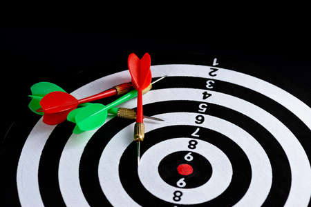 Red and green dart arrow hitting target center Dart board Isolated on black background, Setting aim goal achievement concept challenging business goals And ready to achieve goal and Marketing conceptの写真素材