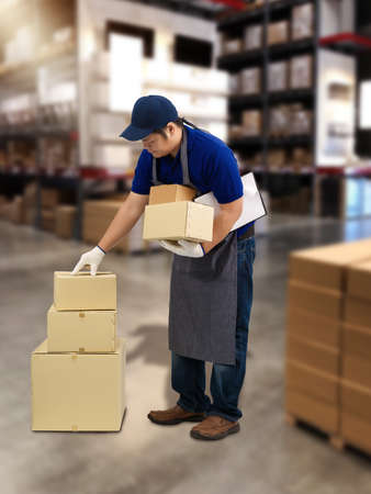 Male staff and parcel boxes checking stock or Preparing Goods For Dispatch and Blurred the background of the warehouseの写真素材