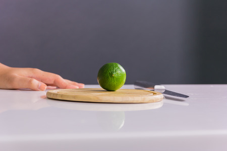 Fresh and sour green lime or lemon, half cut with knife on chopping boardの写真素材