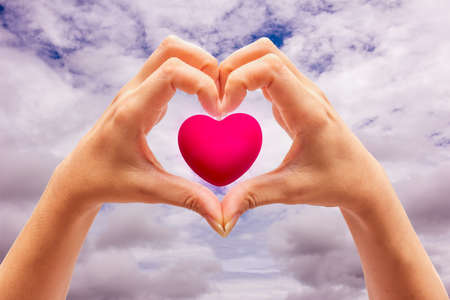Pink Heart in hands on nature background
