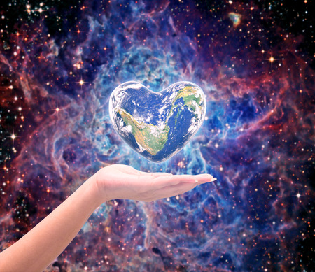 World in heart shape with over women human hands on blurred natural background blue cyan turquoise...
