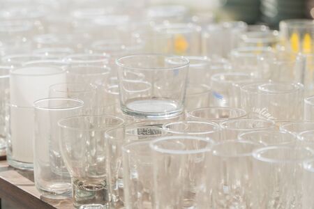 Lots of clean empty glasses of drinks on the bar in a nightclub. Glare and reflections on the glasses in the darkの写真素材