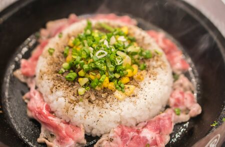 Rice and pork with corn served in hot pan.の写真素材