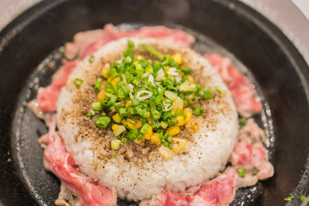 Rice and pork with corn served in hot pan.