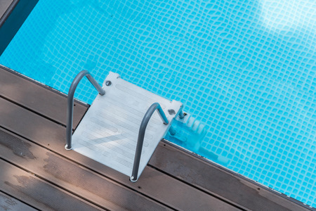 Grab bars ladder in the blue swimming pool.