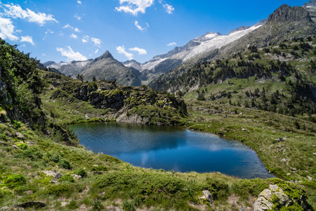 Spectacular, wonderful and evocative landscape of a lake in the Pyrenees surrounded by mountains and snow-capped peaks of Benasque. In HDR colour.の写真素材