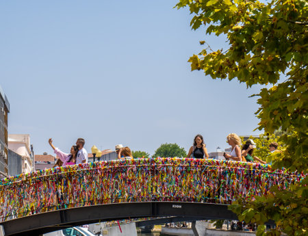 Beautifully and colorfully decorated bridge made of colored paper bows with tourists taking selfies on a canal in Aveiro. Portugal.のeditorial素材