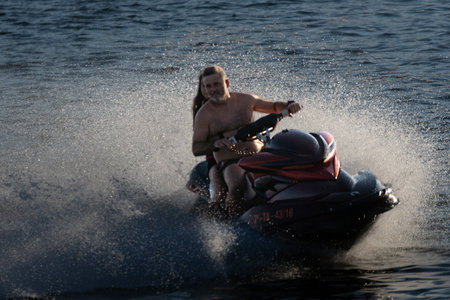 A monitor and a girl enjoying the jet ski skidding at high speed along Boiro beach.のeditorial素材