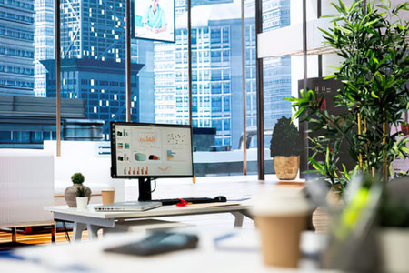 Bright and clean workspace featuring a computer desk, monitor, and chair with a reflective city skyline background.