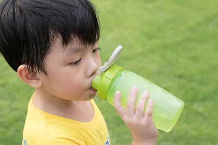 Boy is drinking water from his bottle at the park.の写真素材
