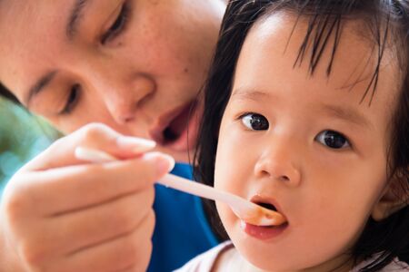 mother feeding breakfast to girl.
