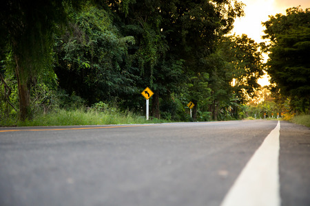 Country asphalt road with traffic sign to the forest.