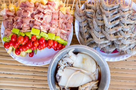 A lot of pork meat, shrimp and squid was made barbecue with chili pepper, tomato and pineapple for dinner party at backyard.の写真素材