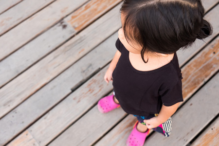Little girl in casual clothes is standing on the old wooden floor for looking for her mother.の写真素材
