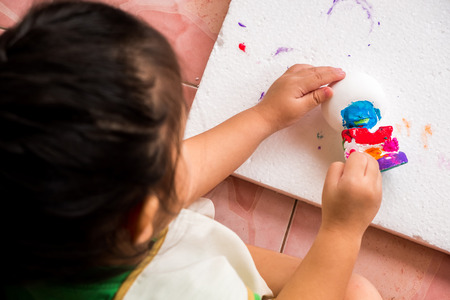 a girl is painting her sculpture with colorful color follow by teacher's instructions. it's fun hobby for preschool children for learn about colors and shape.の写真素材
