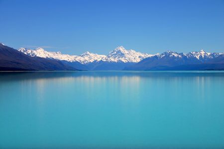 Beautiful mountain turquoise color lake, blue sky and snow peaks reflecting in the water. Untouched...