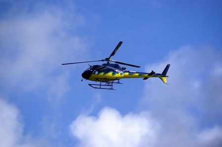 Yellow-blue Helicoper in the sky flying high. Side view.の写真素材