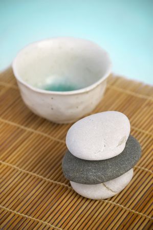 Tranquil Zen style scene. Ceramic cup and pebbles on bamboo matの写真素材