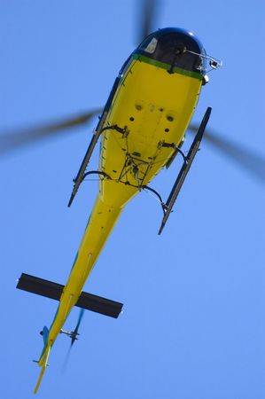 Yellow helicopter in blue sky closeup bottom viewの写真素材