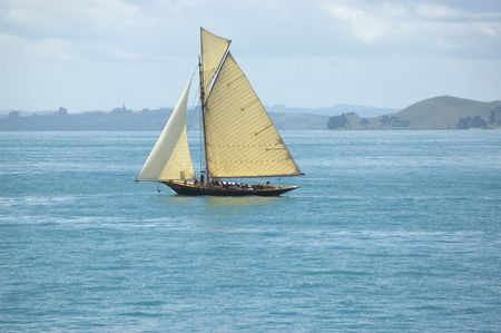 Vintage leisure sail boat with tourists on vacation cruising around islands along sea shoreの写真素材