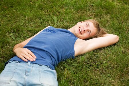 Smiling boy lying on the green grassの写真素材