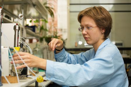 The young nice woman-scientist work with syringe on a background scientific instruments