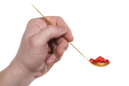 The hand holds a teaspoon with red pills. Isolated on white [with clipping path].の写真素材
