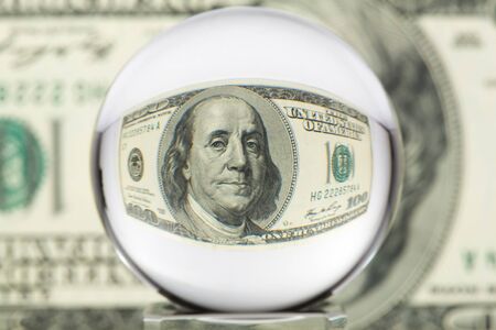 Hundred dollar banknote through glass sphere. Blur background.の写真素材