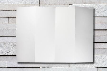 blank folded paper on stone tile wall textureの写真素材