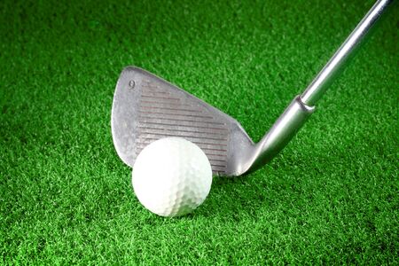 golf iron and golf ball on green grassの写真素材