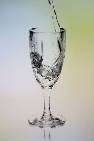 pouring water into wine glass on colorful blurred backgroundの写真素材