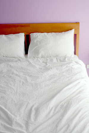 white bed with light purple wall in the morning