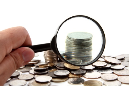 hand holding magnifier looking at coin stackの写真素材