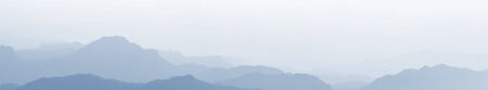 panoramic view of silhouette mountains under mist in the eveningの写真素材