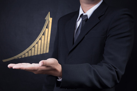 business man showing golden rise arrow with graphの写真素材
