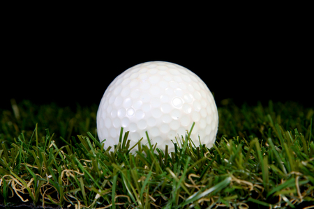golf ball on a tee on black backgroundの写真素材