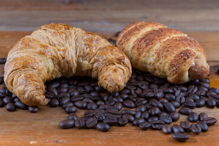 croissant, sausage dough and coffee beans on wooden tableの写真素材