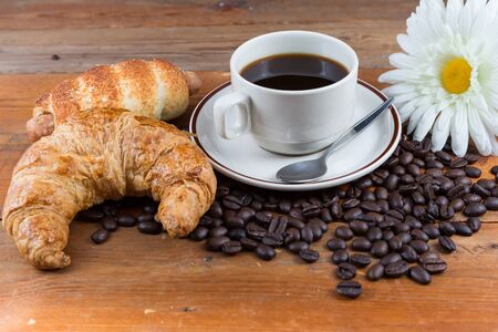 Breakfast with coffee, croissant and sausage dough on wooden tableの写真素材