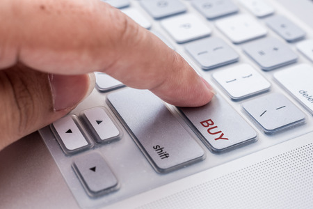 hand pressing "buy" button on computerの写真素材