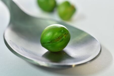 Close-up peas in spoon on a white backgroundの写真素材