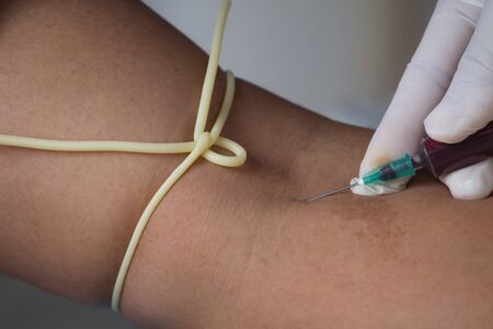 Close-up Of Doctor Injecting Patient With Syringe To Collect Bloodの写真素材