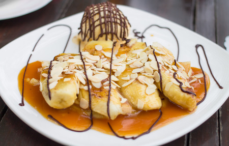 Banana crepe caramel with ice-cream on white plateの写真素材
