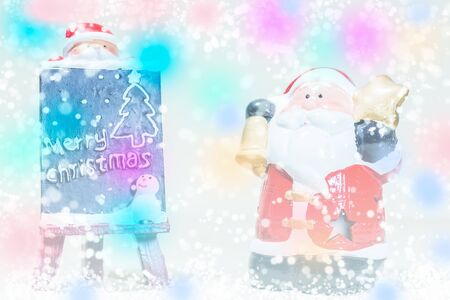 Santa Claus standing in the snow fake with a blackboard on colorful backgroundの写真素材