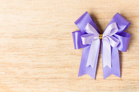 Purple ribbon bow  on wooden background