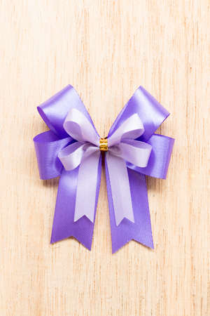 Purple ribbon bow  on wooden background