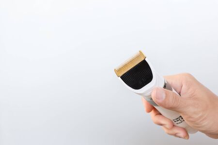 Hand holding hair clippers on grey backgroundの写真素材