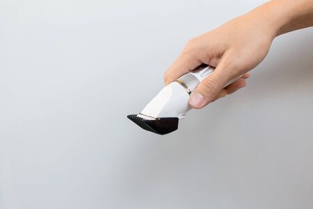 Hand holding hair clippers on grey backgroundの写真素材