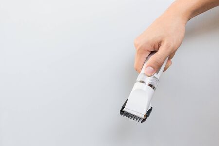 Hand holding hair clippers on grey backgroundの写真素材