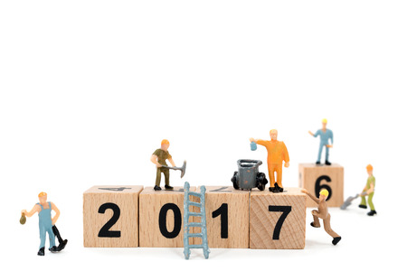 Miniature worker team building wooden block number 2017 on white background
