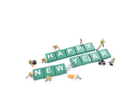 Miniature worker team building word happy new year on white backgroundの写真素材